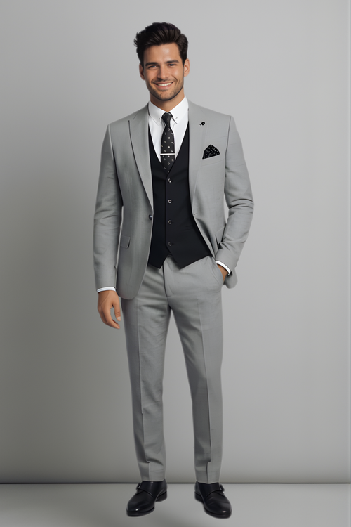 Man wearing a gray suit with a white shirt and black vest against a plain background