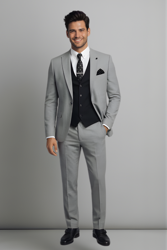 Man wearing a gray suit with a white shirt and black vest against a plain background