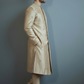 Man wearing a beige traditional outfit against a gray background
