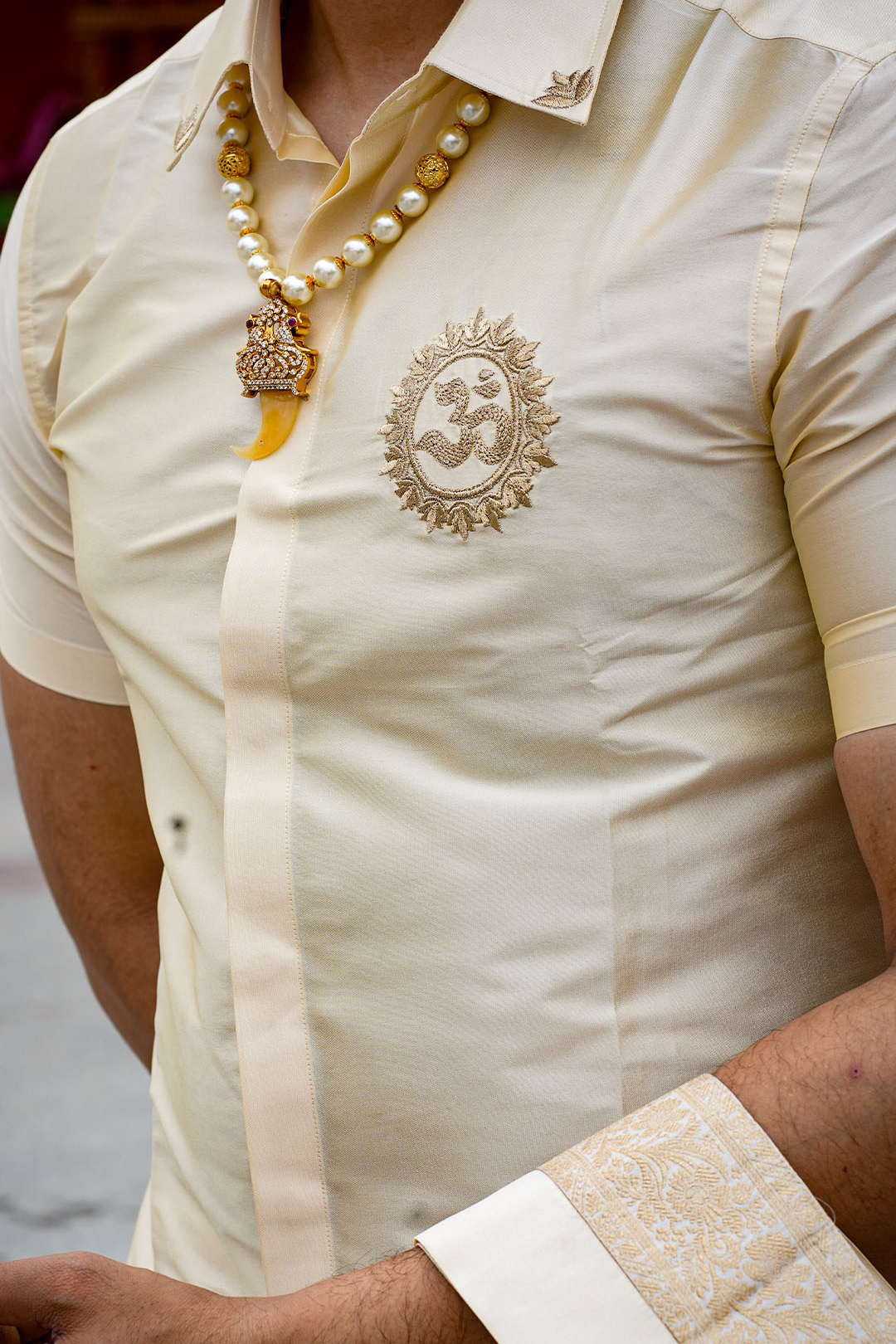 Beige shirt with embroidered design and pearl necklace