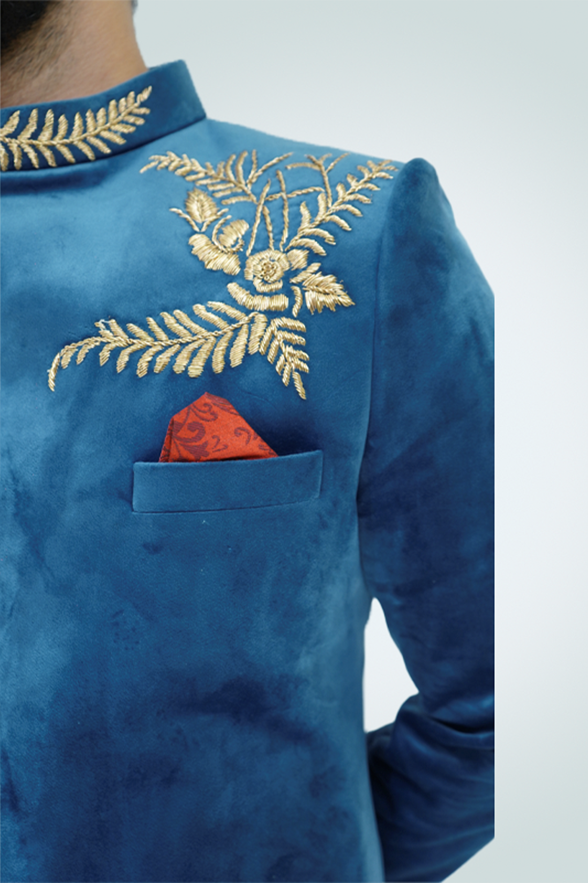 A man wearing a Teal Blue Velvet Jodhpuri with gold embellishments.