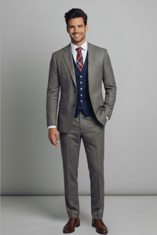 Man wearing a gray suit with a blue vest and red tie against a plain background