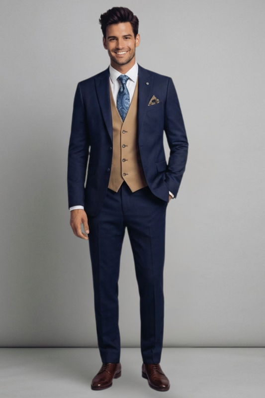 Man wearing a navy suit with a beige vest and brown shoes on a gray background