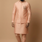 Man wearing a peach traditional outfit against a beige background