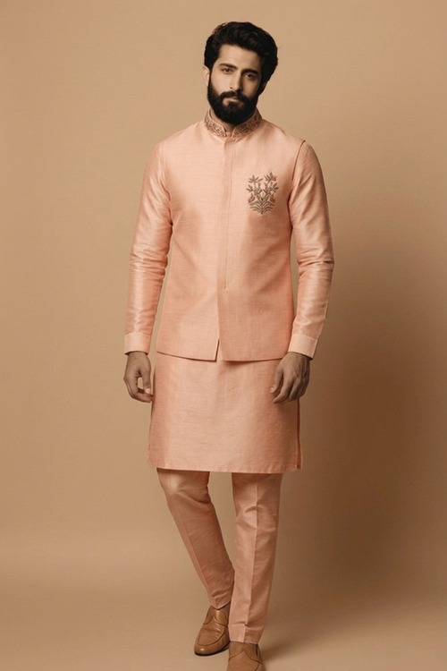 Man wearing a peach traditional outfit against a beige background