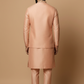 Man wearing a peach traditional outfit against a beige background