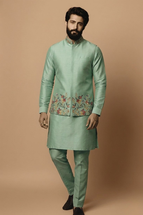 Man wearing a traditional green kurta with floral embroidery on a beige background