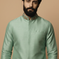 Man wearing a light green kurta with floral embroidery on a beige background