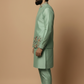 Man wearing a green embroidered traditional outfit on a beige background