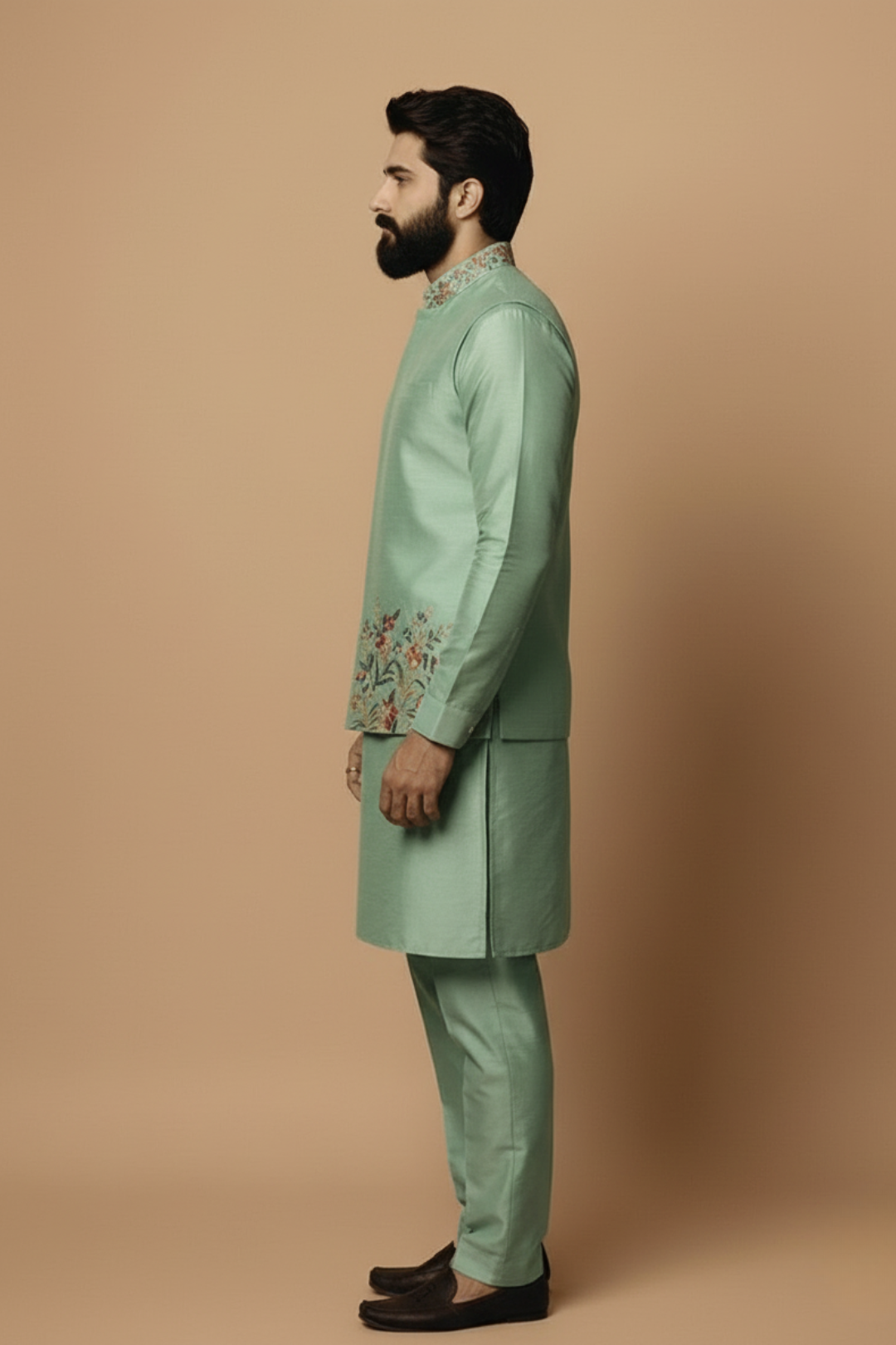 Man wearing a green embroidered traditional outfit on a beige background