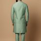 Man wearing a green traditional outfit against a beige background