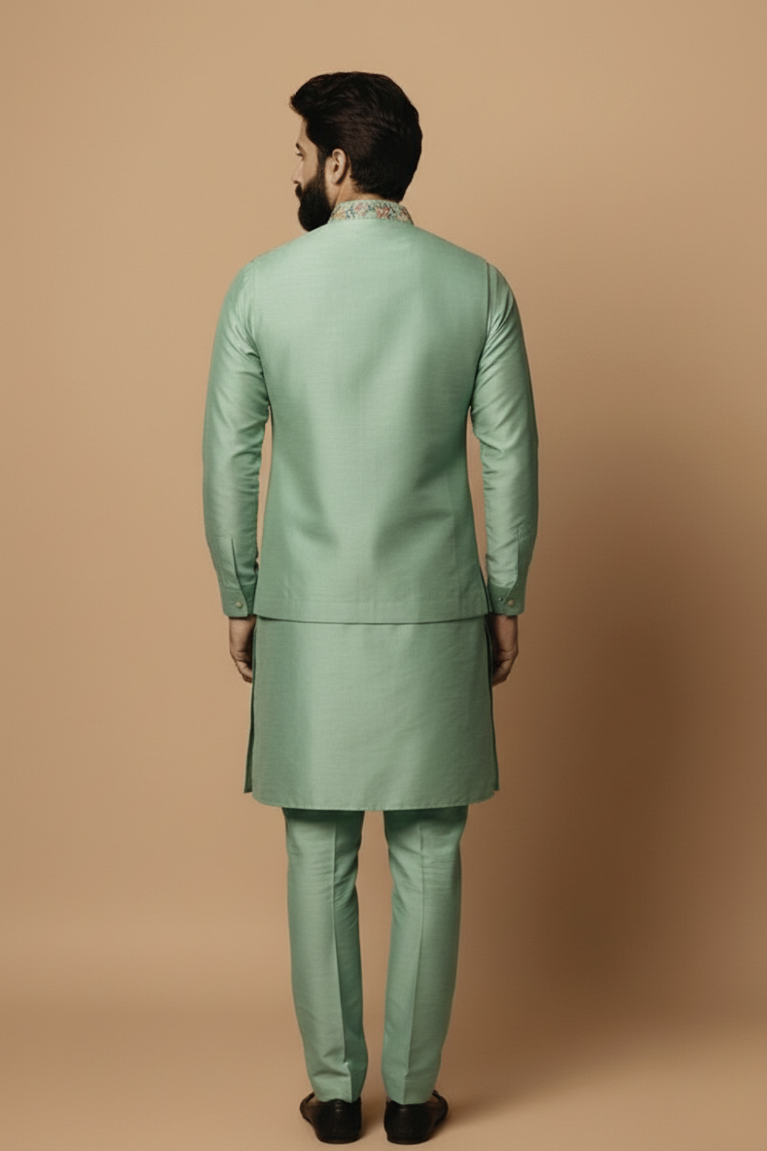 Man wearing a green traditional outfit against a beige background