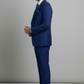 Man wearing a blue suit standing against a plain background