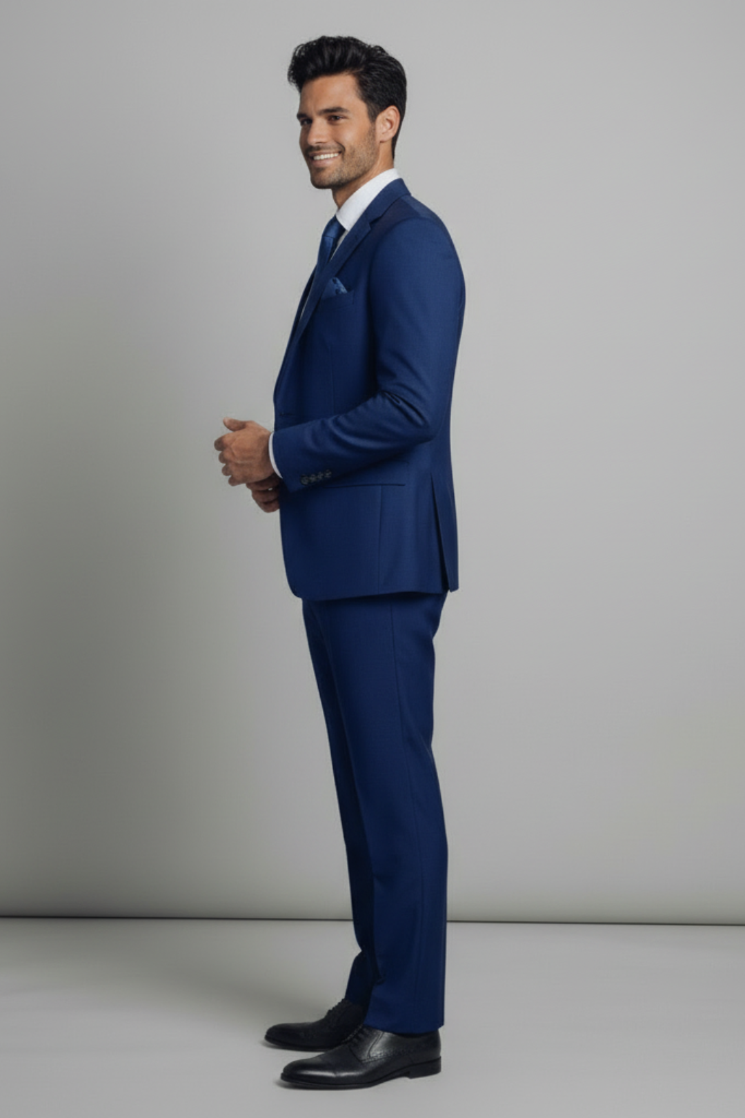 Man wearing a blue suit standing against a plain background