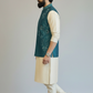Man wearing a teal embroidered vest over a cream kurta with beige pants on a light gray background