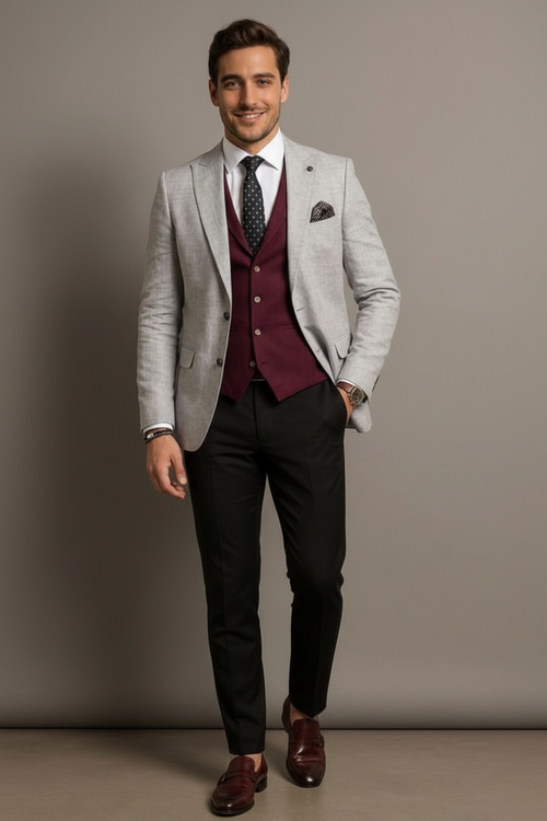 Man wearing a gray suit with a maroon vest and black pants against a plain background
