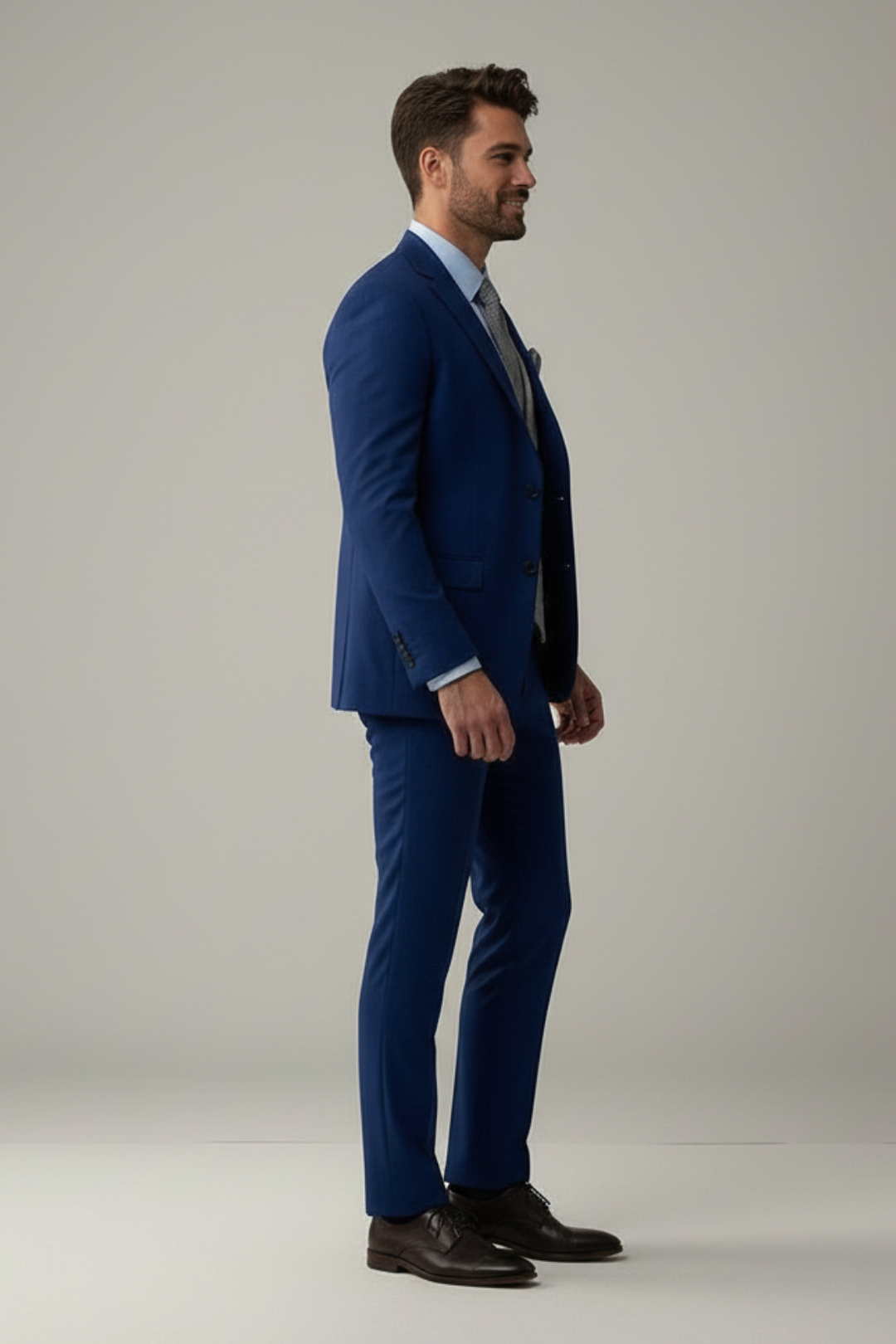 Man wearing a blue suit standing against a plain background