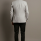 Man wearing a light gray checkered blazer and black pants against a plain background