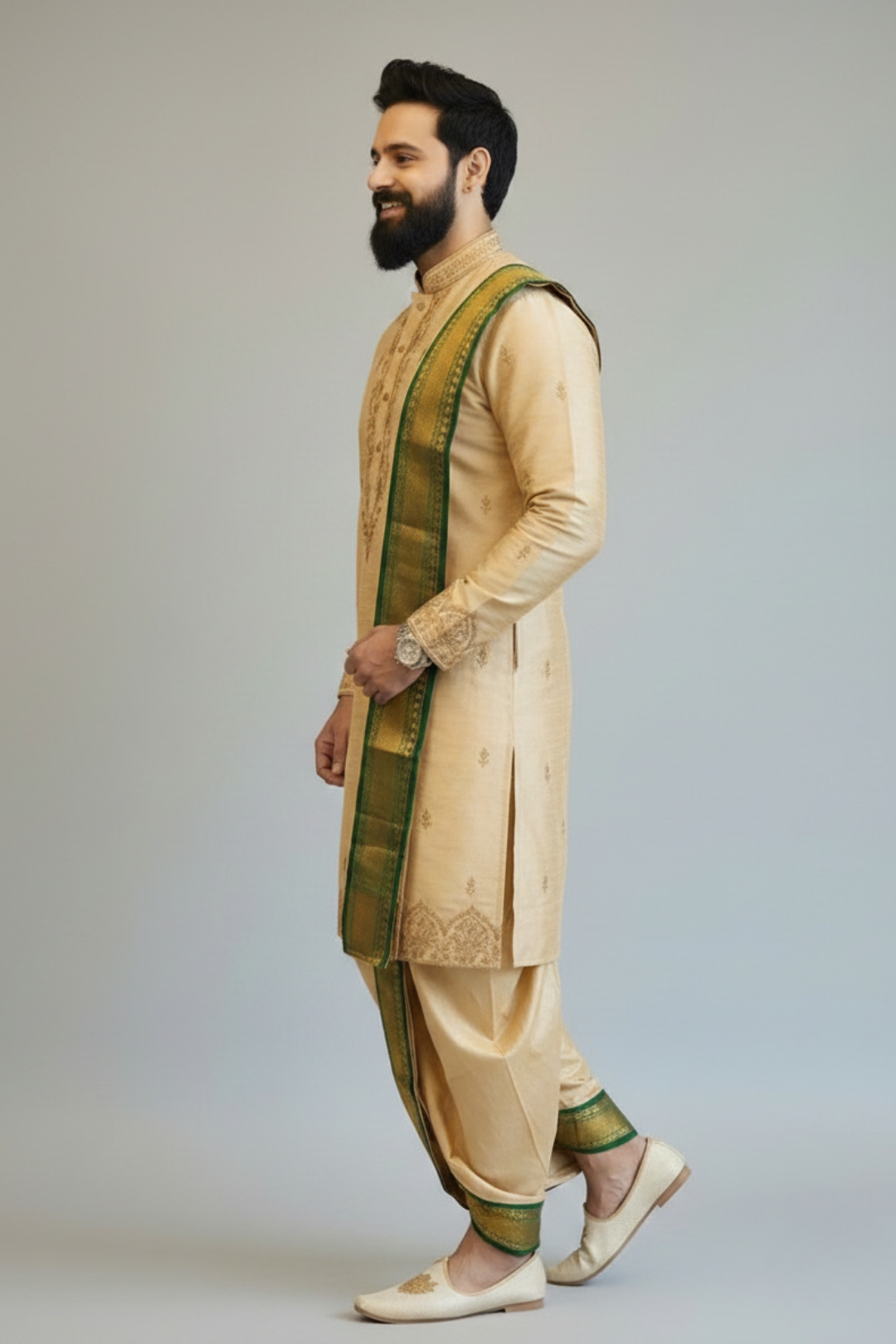 Man wearing a traditional beige and green sherwani against a plain background