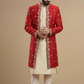Man wearing a red sherwani with white patterns on a beige background