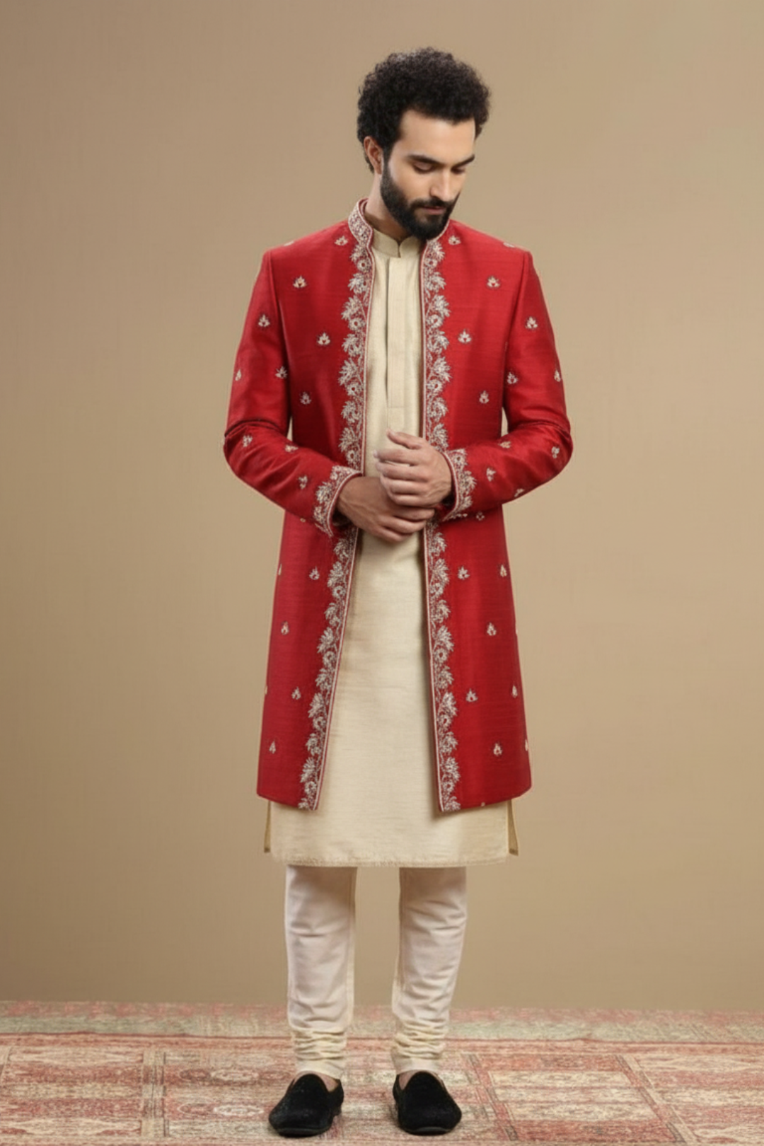 Man wearing a red sherwani with white patterns on a beige background