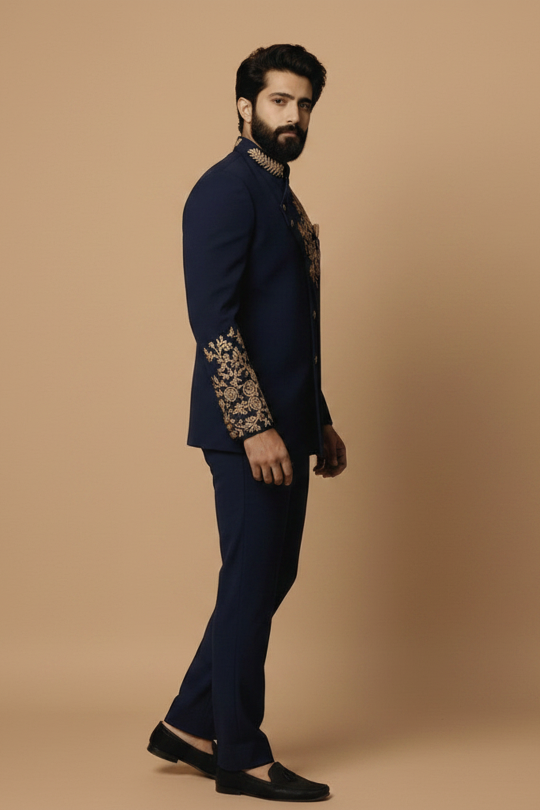 Man wearing a navy blue suit with gold embroidery on a beige background