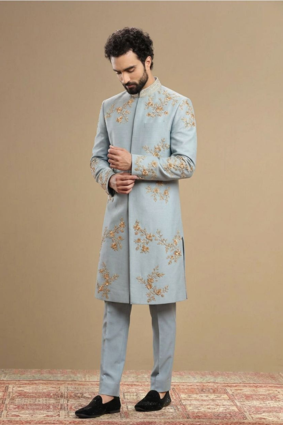 Man wearing a light blue embroidered sherwani against a beige background