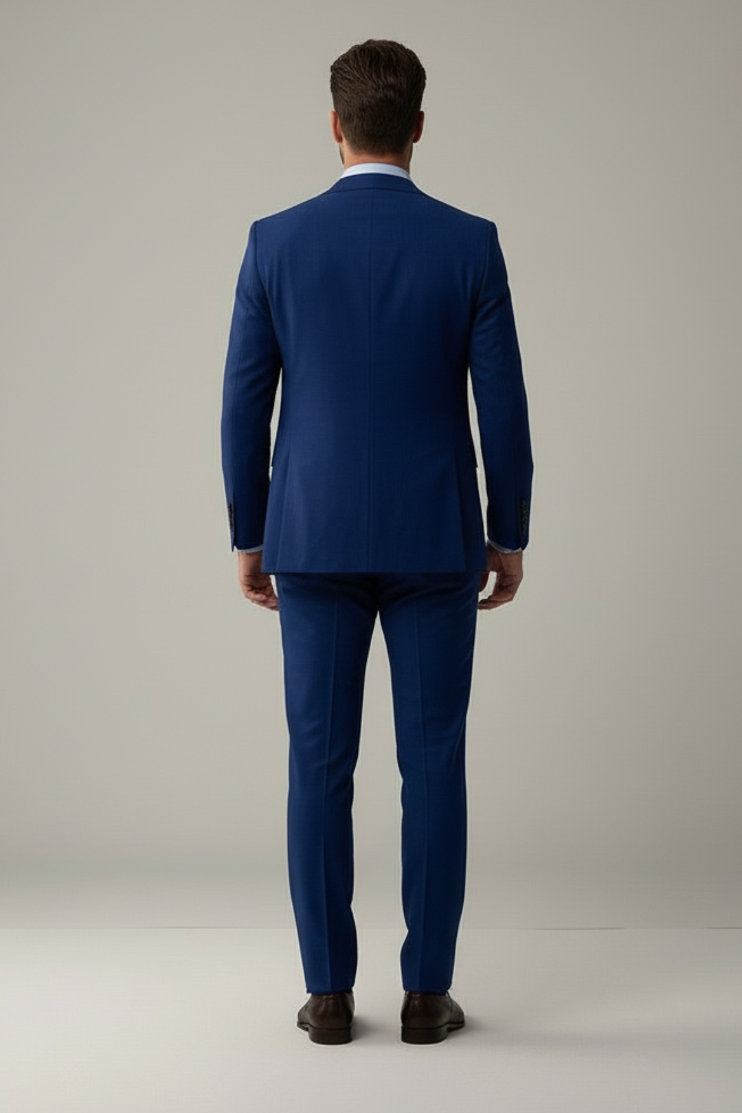 Man wearing a blue suit standing against a plain background