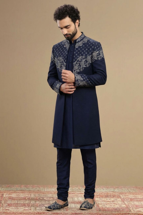 Man wearing a navy blue sherwani with intricate patterns on a beige background