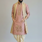 Man wearing a traditional pink kurta with gold embroidery and a beige scarf on a plain background