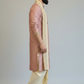 Man wearing a traditional pink and cream sherwani with a white background