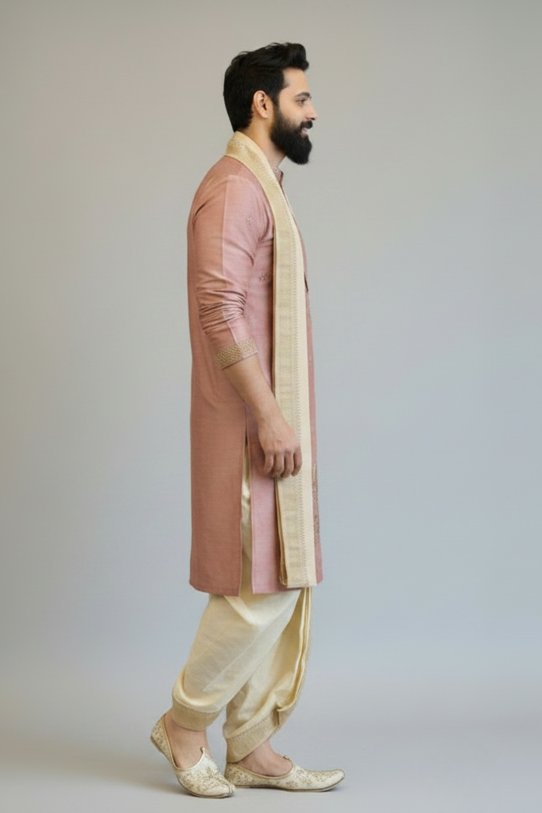 Man wearing a traditional pink and cream sherwani with a white background