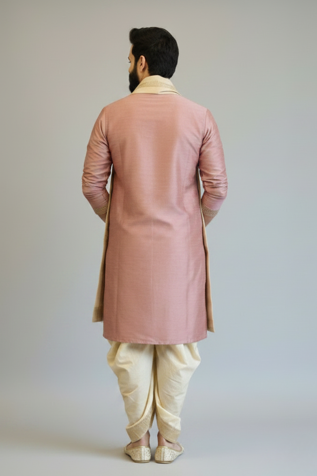 Man wearing a pink sherwani with white pants against a plain background