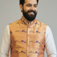 Man wearing a patterned orange vest over a white shirt against a gray background