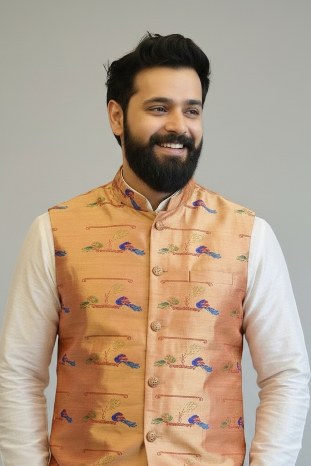 Man wearing a patterned orange vest over a white shirt against a gray background