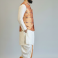 Man wearing a traditional outfit with a vest on a plain background