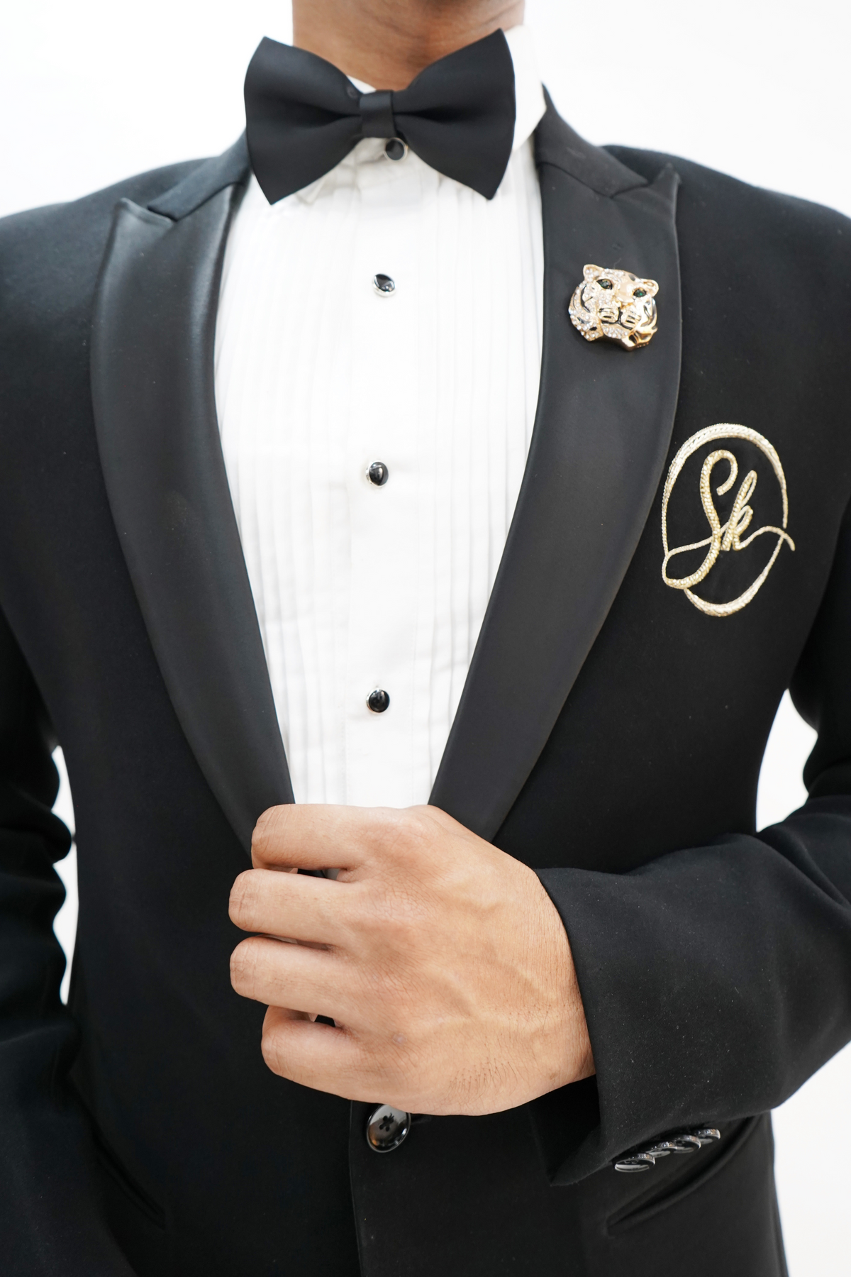 Man wearing a black suit with a white shirt and black bow tie on a plain background