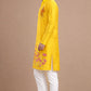 Man wearing a bright yellow kurta with white pants on a beige background