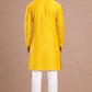 Person wearing a yellow kurta with white pants against a brown background