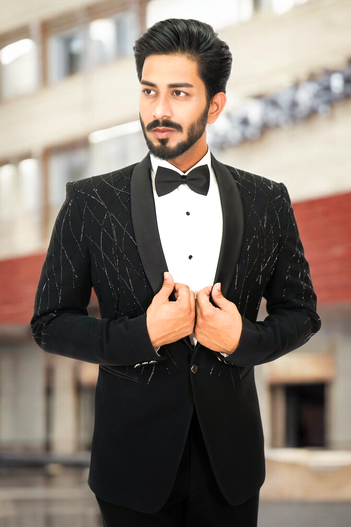 Man wearing a black tuxedo with a bow tie in an indoor setting