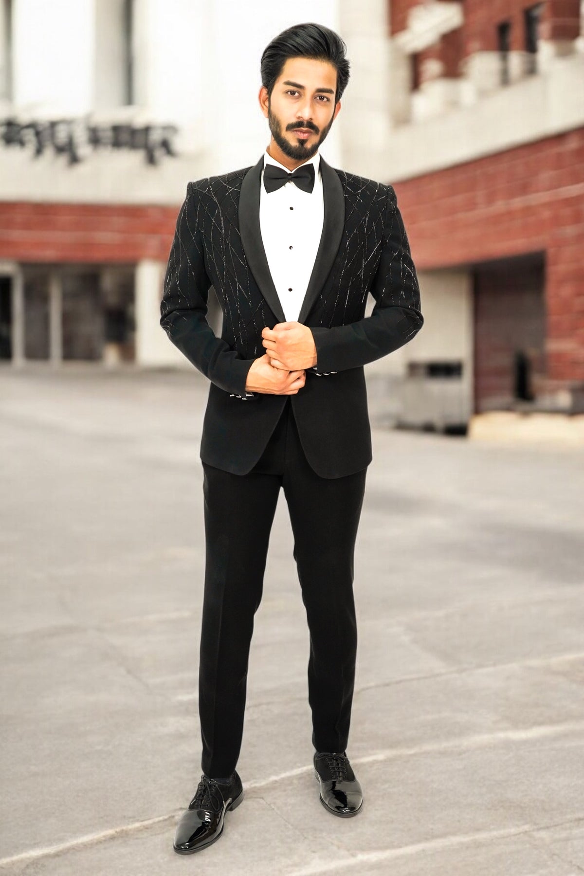 Man wearing a black tuxedo standing on a street.