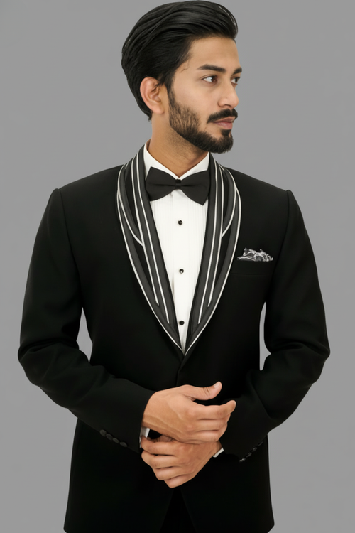 Man wearing a black tuxedo with a white shirt and bow tie on a gray background