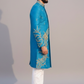 Man wearing a blue embroidered sherwani with white pants on a plain background