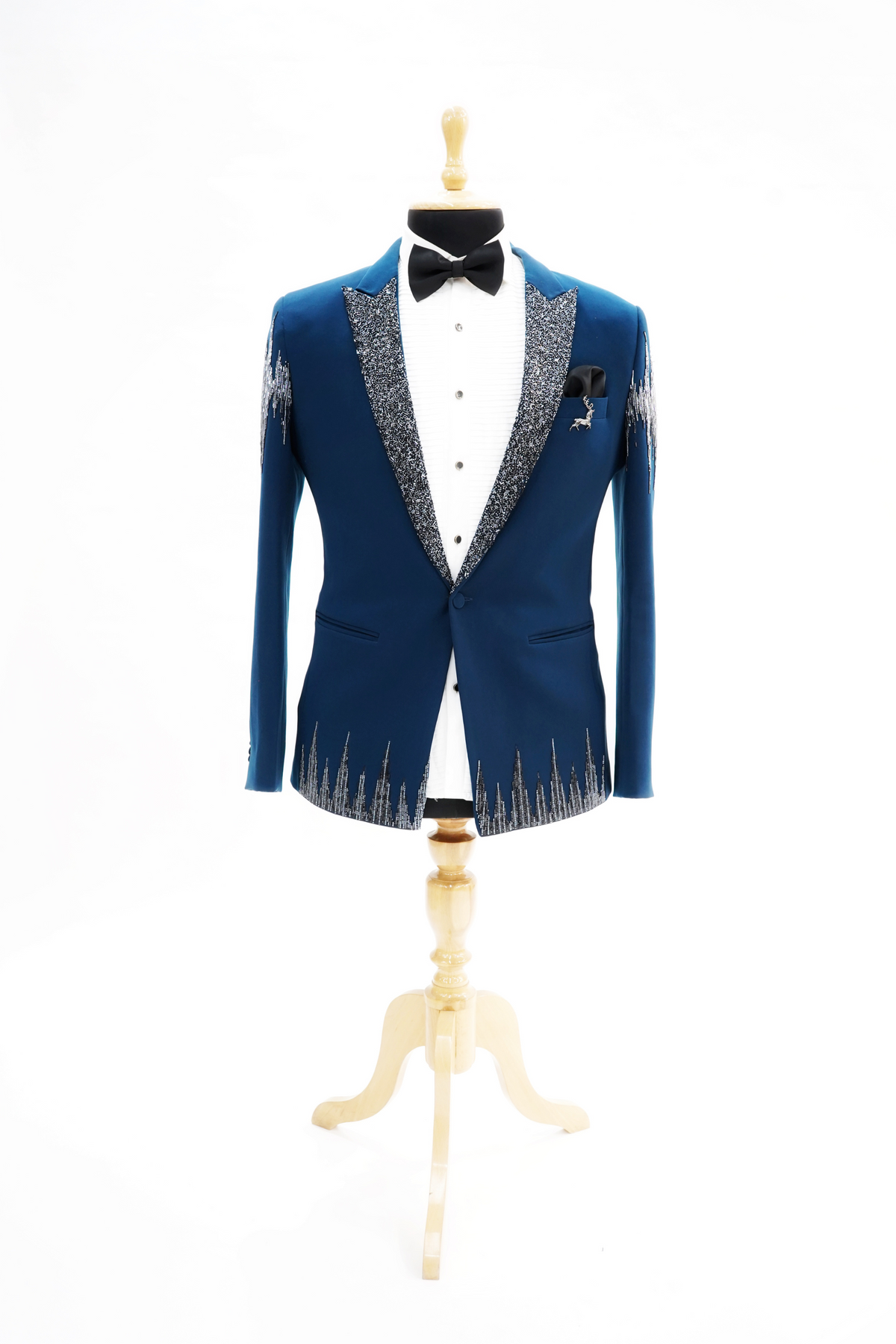 Man wearing a blue tuxedo with silver embroidery on a plain background