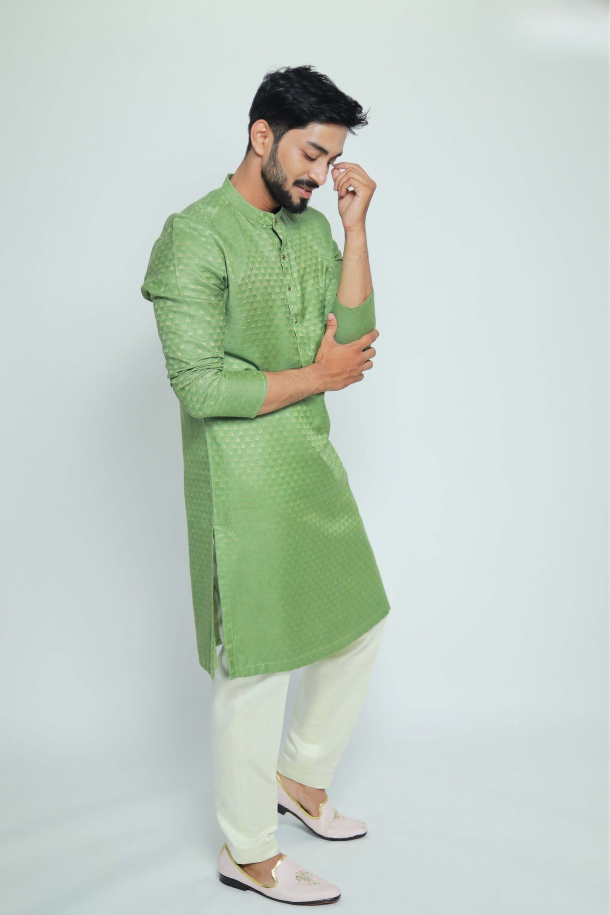 Man wearing a green kurta with white pants on a light gray background