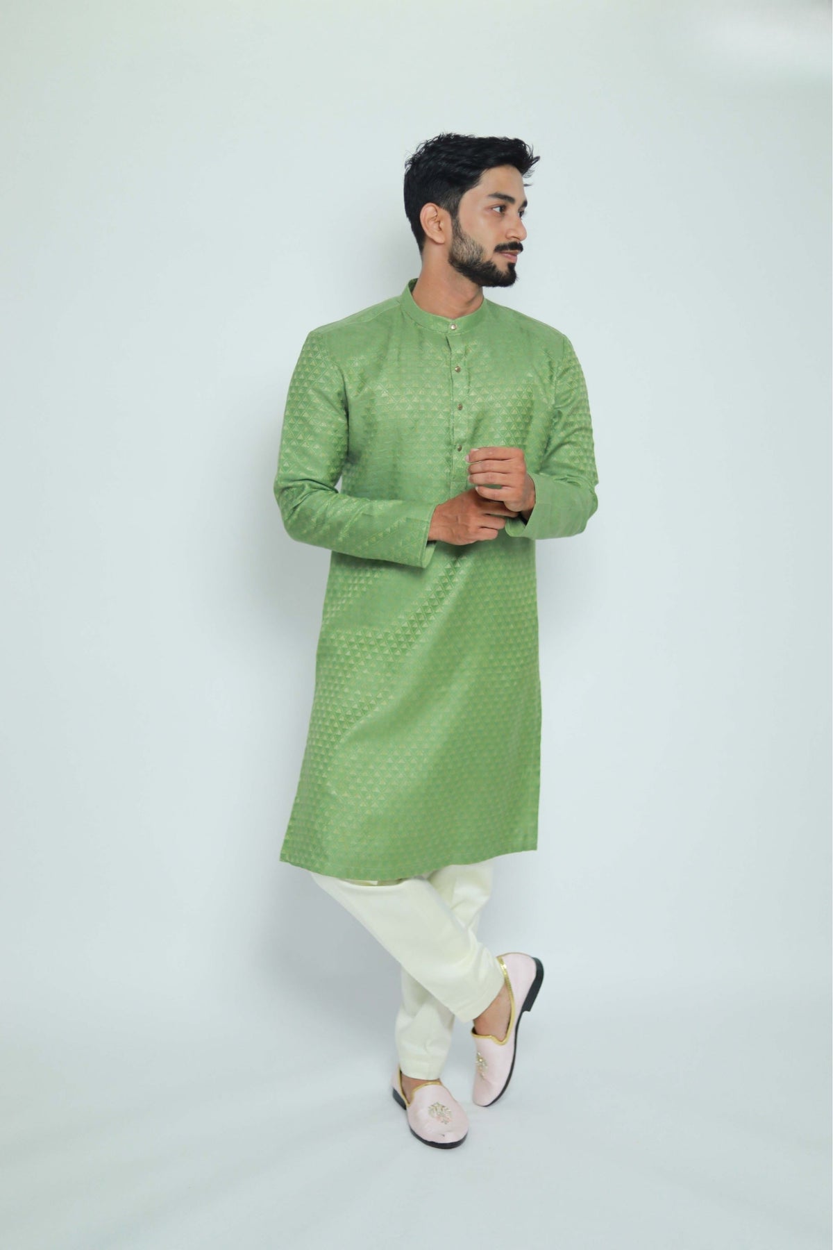 Man wearing a green kurta with white pants on a light gray background