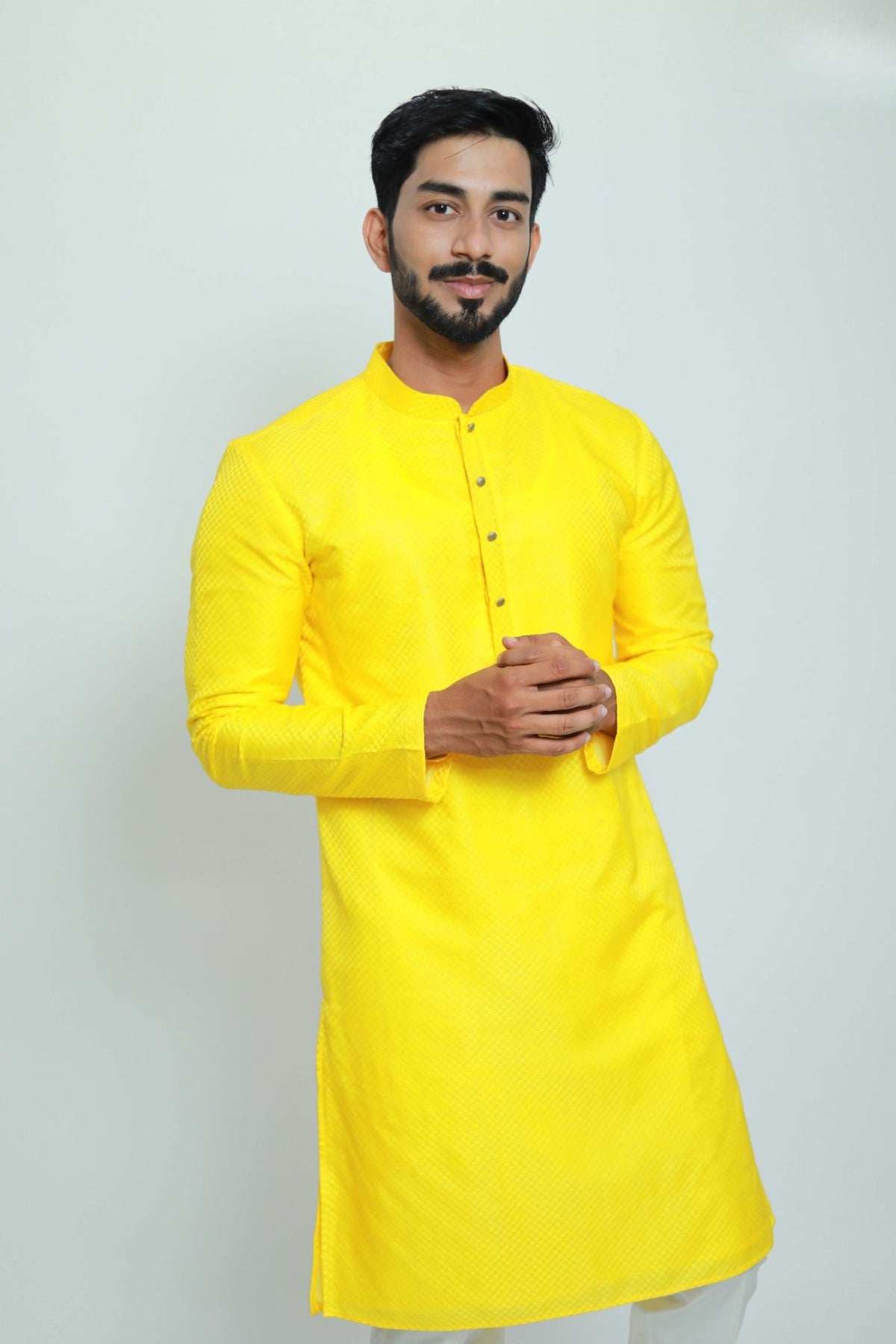 Man wearing a bright yellow kurta against a white background