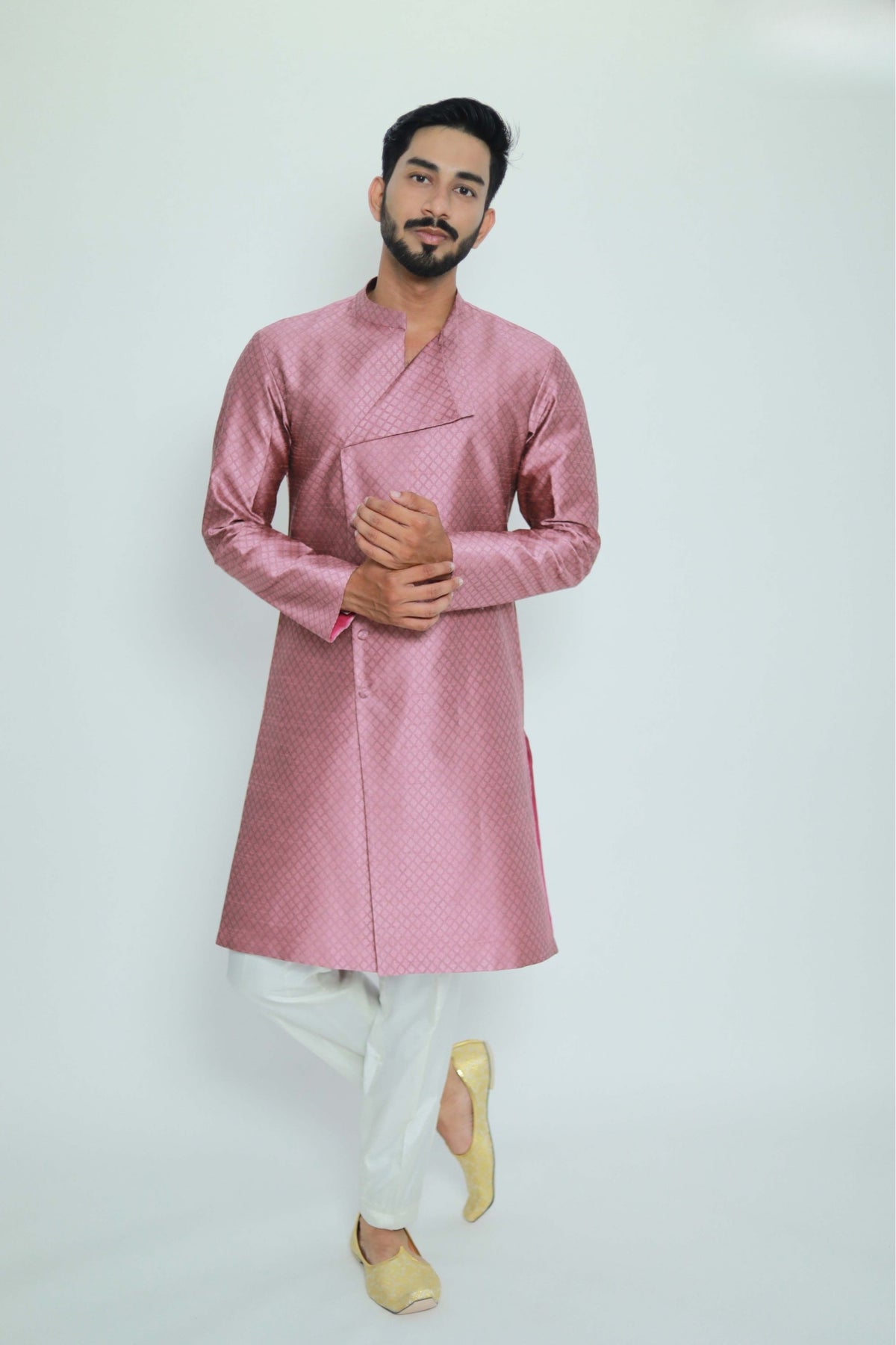 Man wearing a pink kurta with white pants on a light gray background