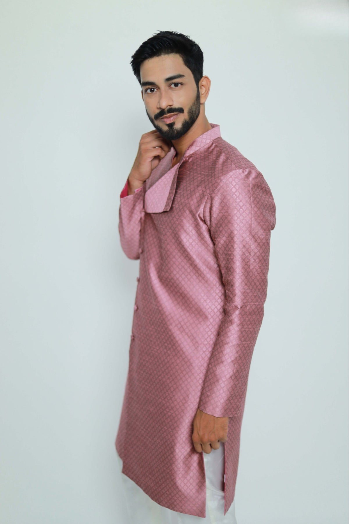 Man wearing a pink traditional outfit against a white background
