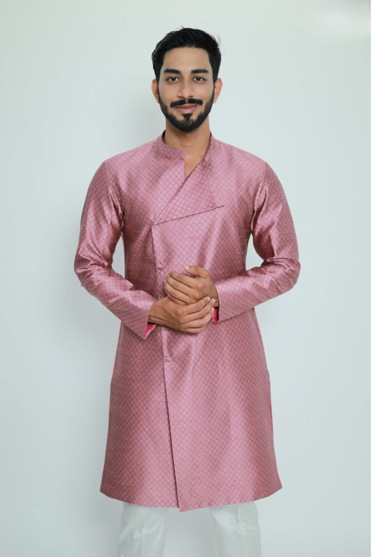 Man wearing a pink traditional outfit against a white background
